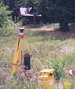 Photograph showing view of domestic well with differential global positioning satellite receiver (on tripod) used for precise determination of well head elevation and electronic tape (red spool with black handle) used to measure depth to water in the well. (Photograph taken by Robin Smith, U.S. Geological Survey, June 2001.)